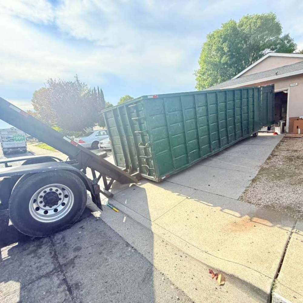 Green roll-off being delivered to a residential driveway